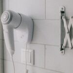 Clean white wall-mounted hair dryer in a contemporary bathroom setting.